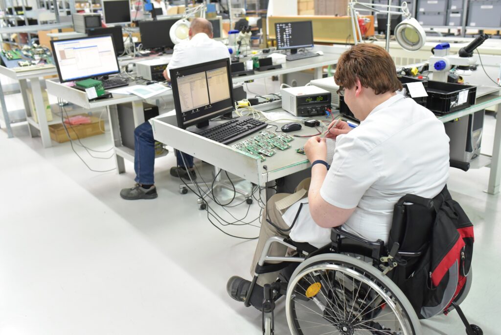 handicapped worker in a wheelchair at a workplace in a electronics manufacturing and assembly factory handicapped worker in a wheelchair at a workplace in a electronics manufacturing and assembly factory